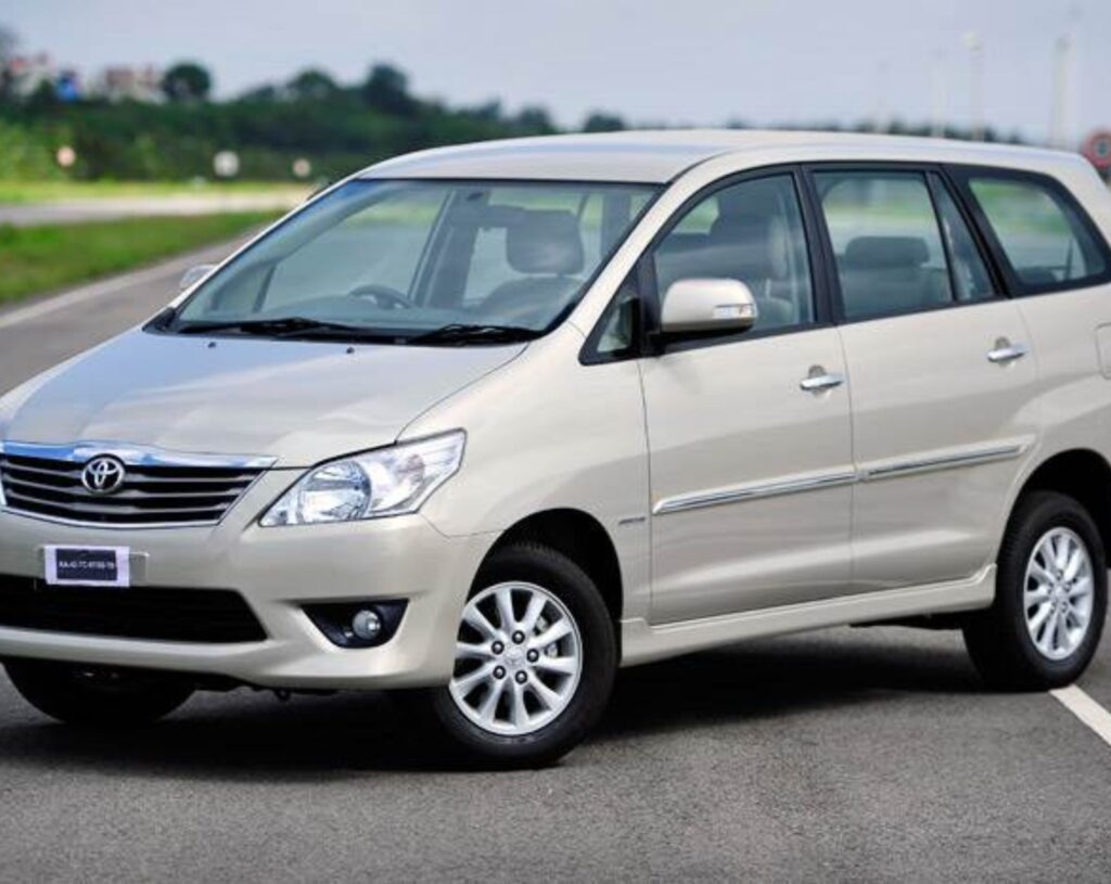 a white innova taxi stopped in middle of road which is used as taxi in trivandrum